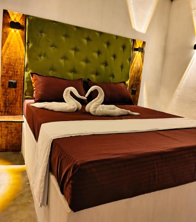 two swans are laying on a bed in a bedroom at Cocos cabana in Ilandaiyadi