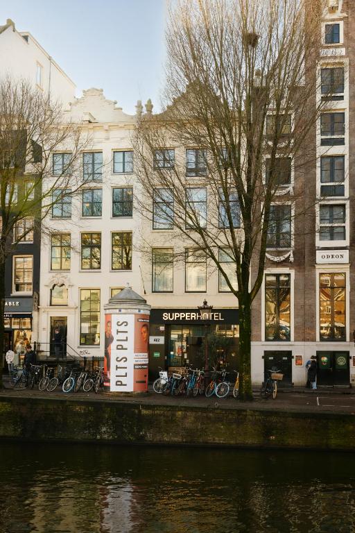 a building with bikes parked in front of a river at SUPPER Hotel in Amsterdam