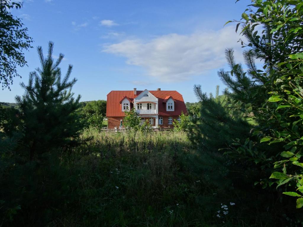 una casa con techo rojo en un campo en Jeleńczówka Alte Dorfschule, en Parchowo