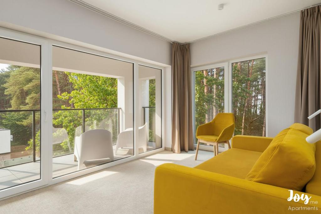 a living room with a yellow couch and windows at Apartamenty Łukęcin Joy me 3 in Łukęcin