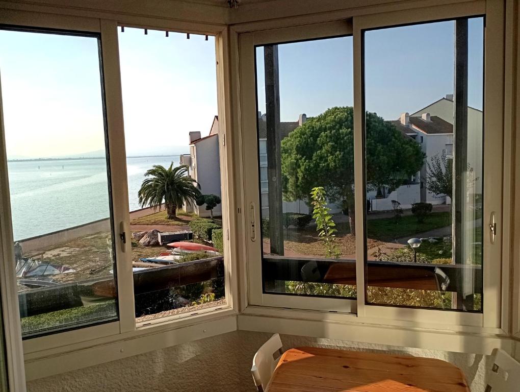 a room with windows looking out at the ocean at les pieds dans l'eau 2 - Piscine chauffée in Le Barcarès