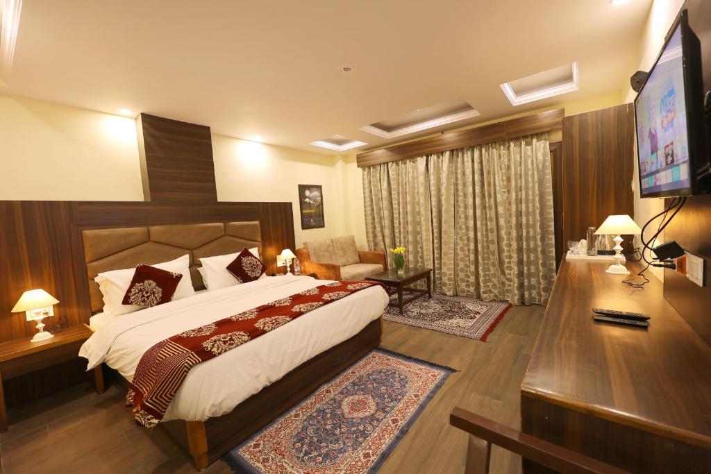a bedroom with a bed and a desk and a television at The Summerlead, Shimla in Shimla