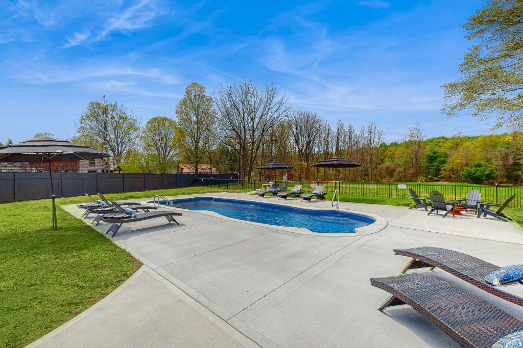 a swimming pool with chairs and umbrellas in a yard at Outdoor Wonderland! Home 12 Mi to Lake George in Fort Ann