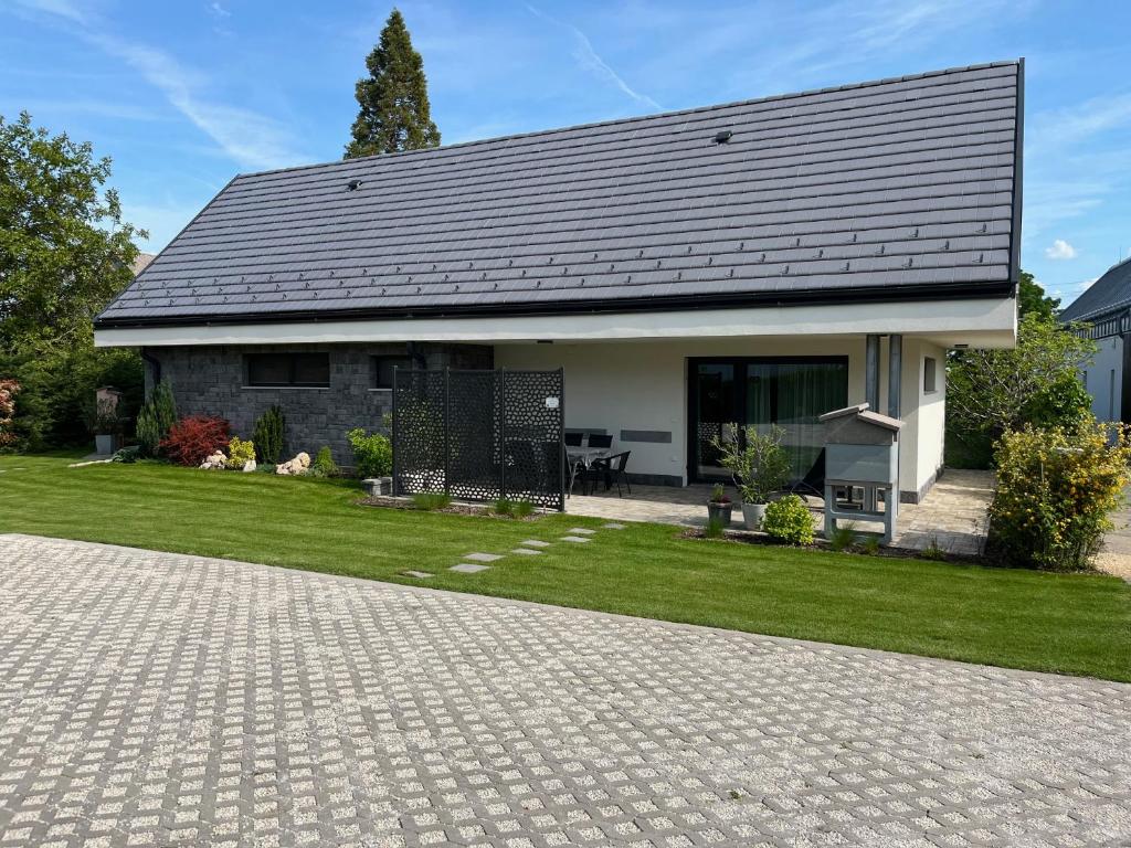 a house with a black roof and a brick driveway at PIHE apartmanok in Balatonfüred