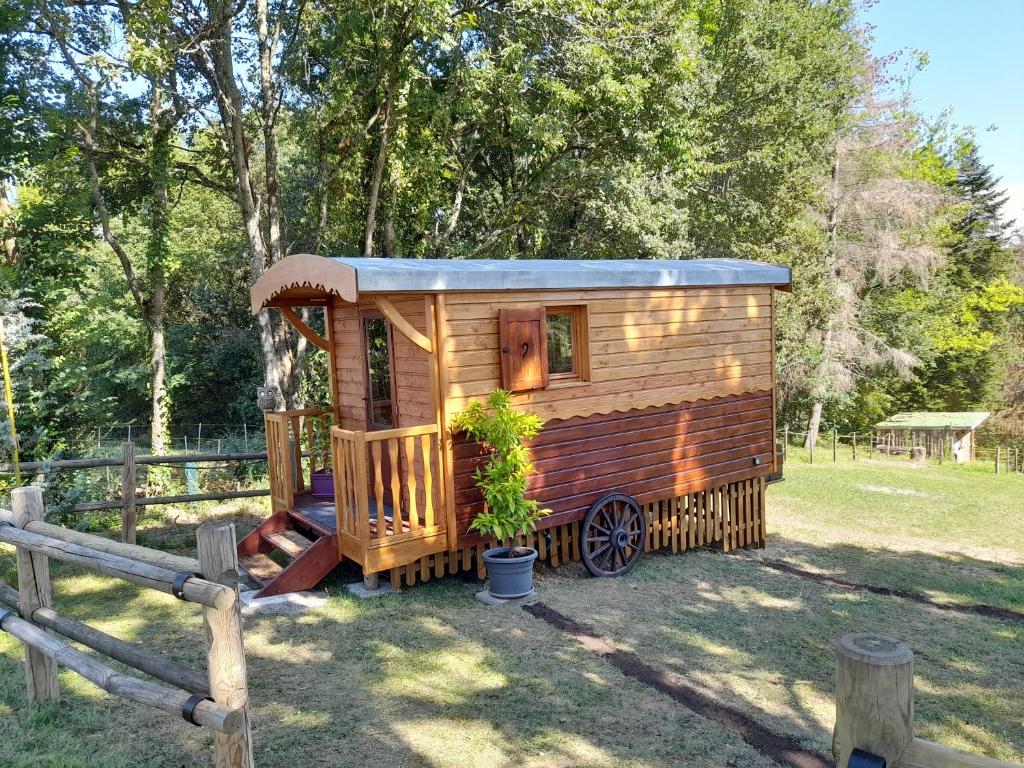 a wooden cabin in a field with a fence at Roulotte Manoé in Liéoux