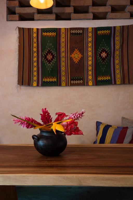 a black vase with flowers on a wooden shelf at Casa Maradi-Arena in Mazunte