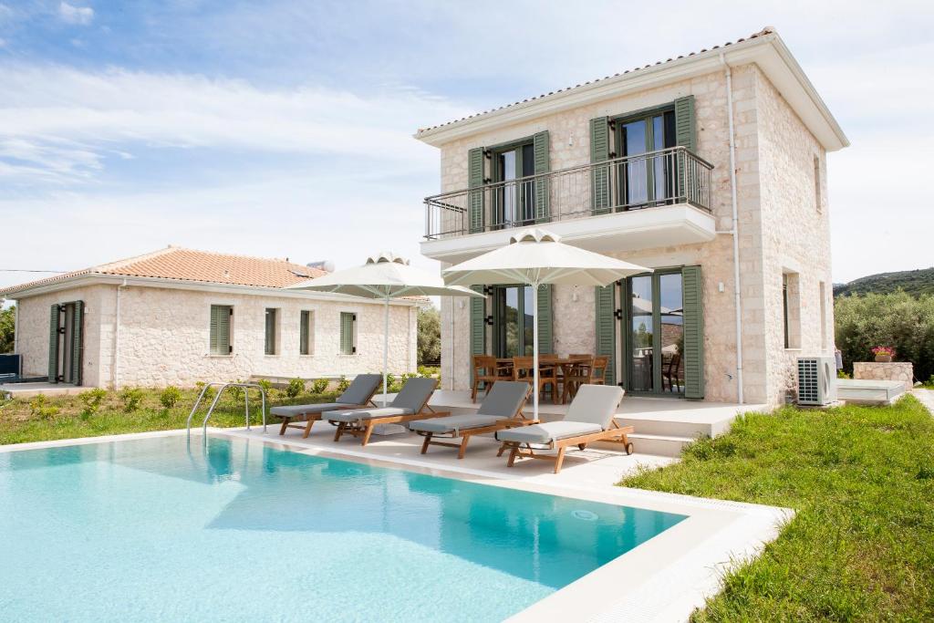 a villa with a swimming pool in front of a house at Anagallis Villas in Lefkada