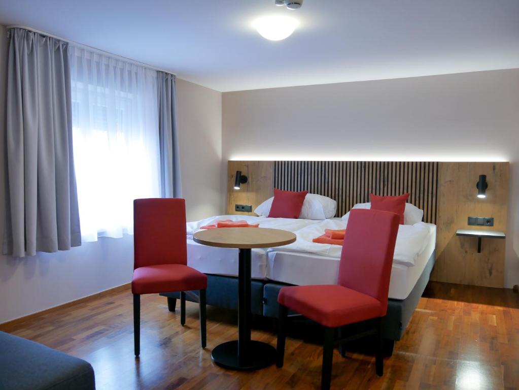 a hotel room with a bed and a table and chairs at Hotel Linde-Sinohaus in Lustenau
