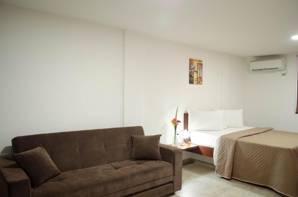 a living room with a couch and a bed at Hotel El Faro Buga in Buga