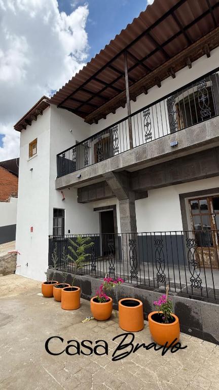 a white building with orange flower pots in front of it at Suite Matlazinca by Casa Bravo in Toluca