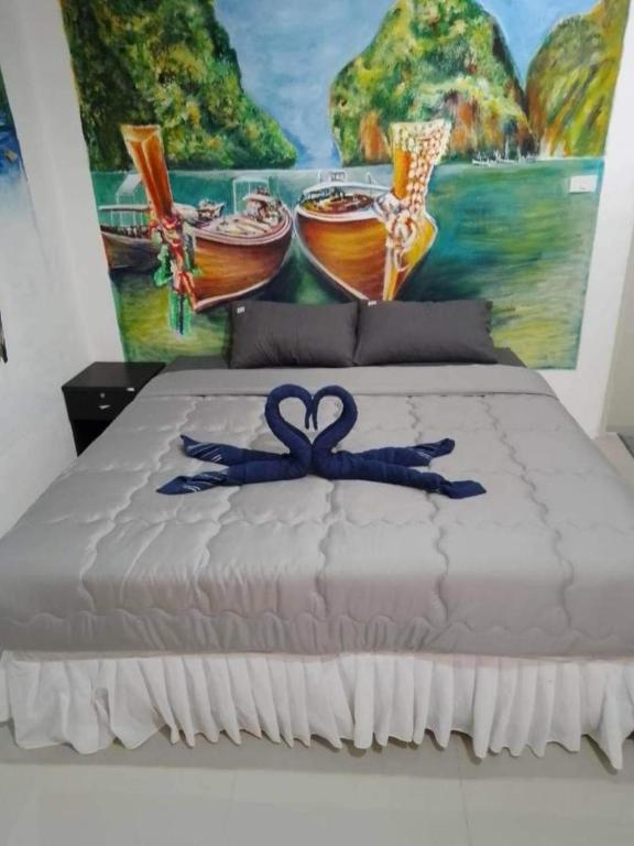 a bed with a blue ribbon on it with a painting at Reggaein in Phi Phi Islands