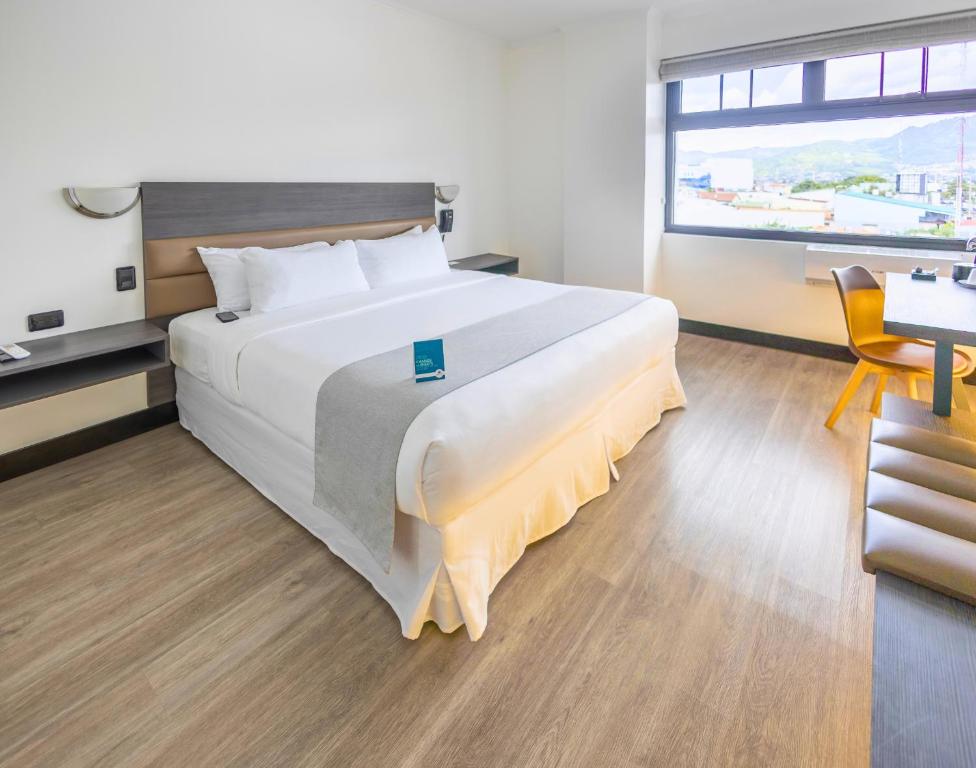 a bedroom with a large bed with a large window at Parque del Lago Boutique Hotel in San José
