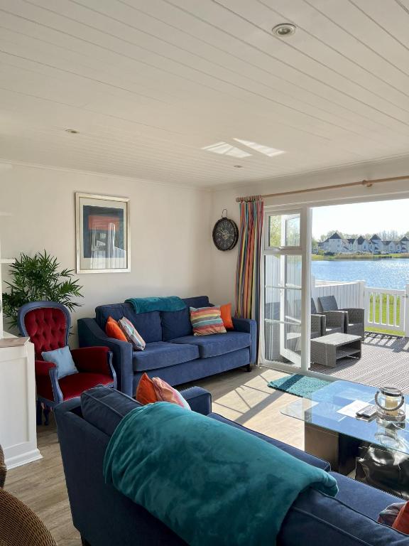 a living room with a blue couch and a table at Lakefront Lodge w SUP & Fishing Access Cotswolds in Gloucestershire