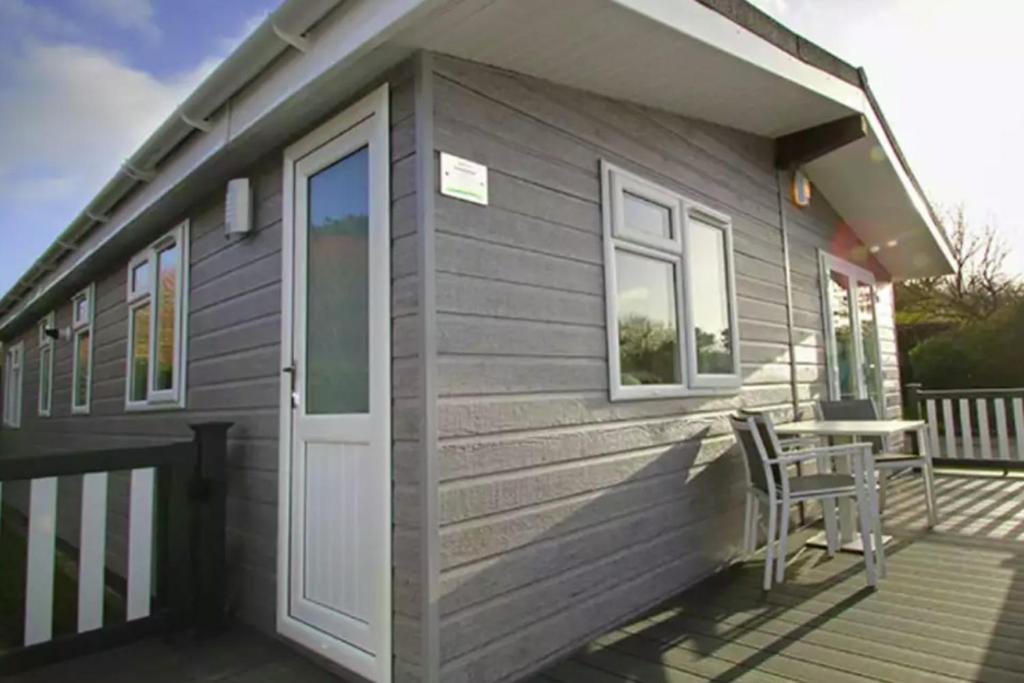 a tiny house with a door and a chair on a deck at Forest Edge 4 Bedroom Select Lodge in Saint Leonards