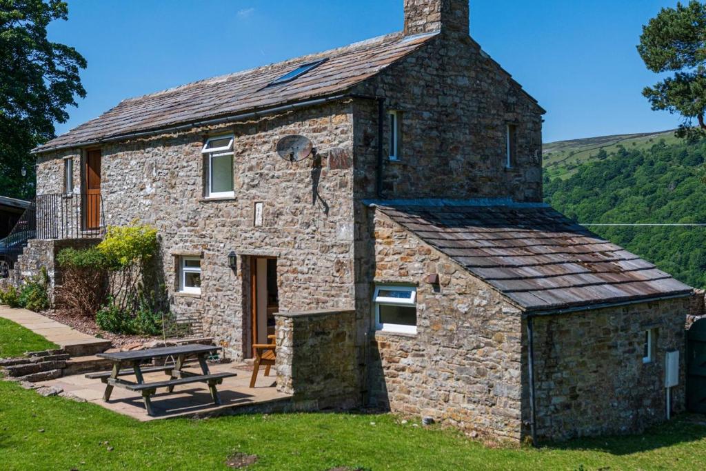 a stone house with a picnic table in front of it at 2 Bed in Low Row oc-ds1010 in Gunnerside