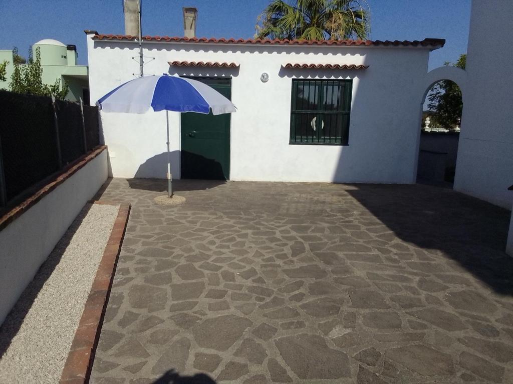 Ein blauer Regenschirm steht vor einem weißen Haus in der Unterkunft Le 5 querce in Nettuno