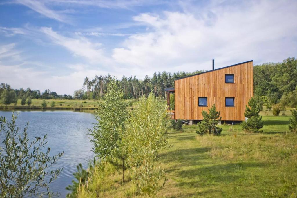 a wooden house next to a body of water at RESORT SALIXA u Poděbrad in Poděbrady