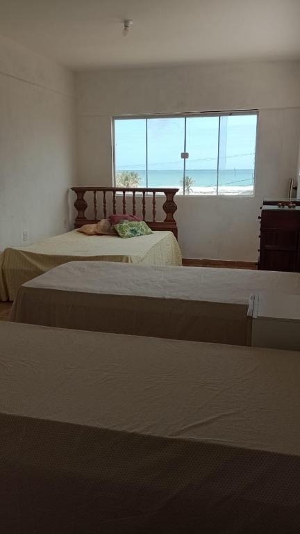 two beds in a bedroom with a view of the ocean at Casa da barra in Canguaretama