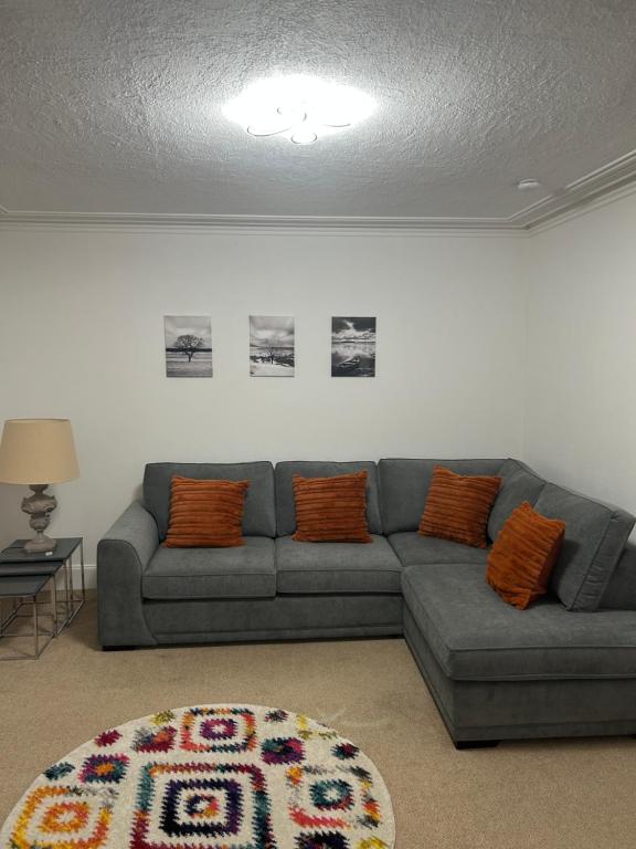 a living room with a gray couch and orange pillows at Mortlach Cottage in Dufftown