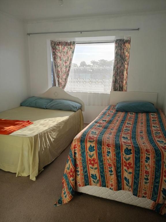 two beds in a room with a window at Budget accommodations 2 in Papamoa