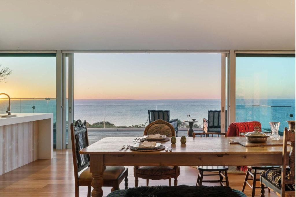 a dining room with a table and a view of the ocean at The Veranda - Panoramic Bay Views Private Beach Access Pool in Mount Eliza