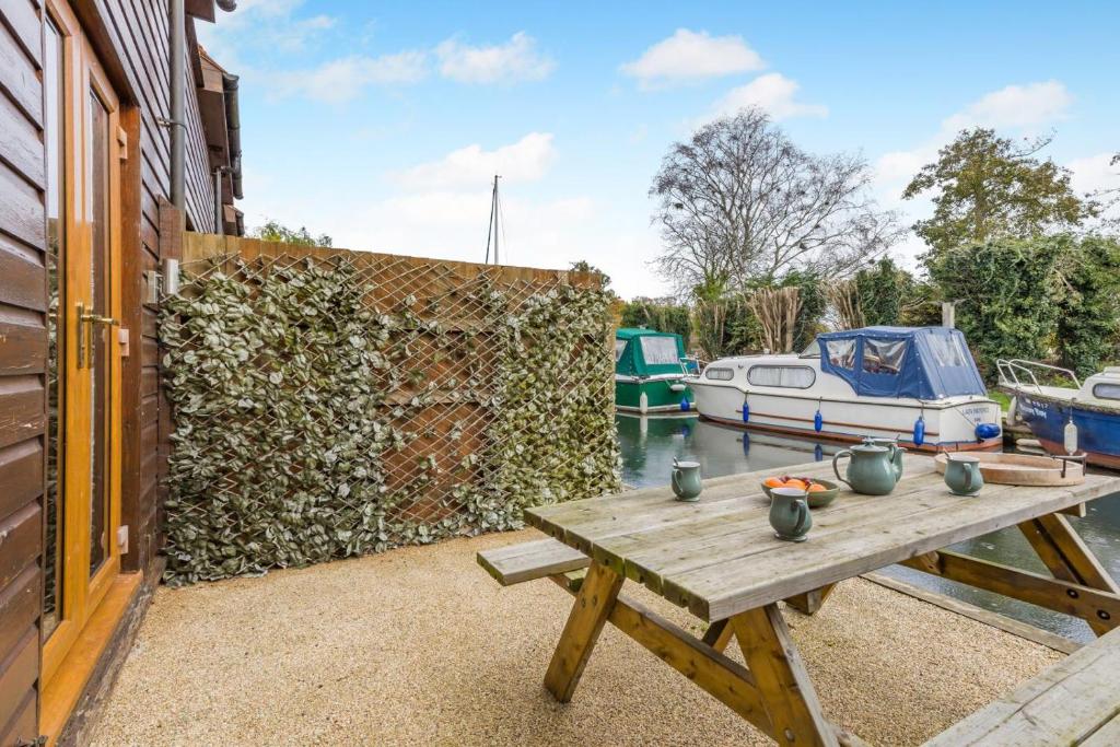 a wooden picnic table next to a wall with boats at 2 Bed in Smallburgh oc-h33734 in Dilham