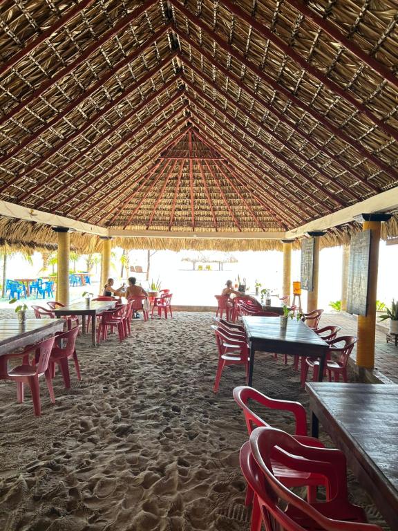 a restaurant with tables and chairs and a straw roof at Terra Tipi in Guayabas
