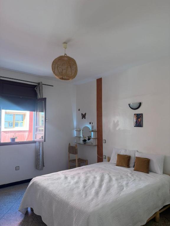 a bedroom with a white bed and a window at Dar Laila Surf in Tamraght Ouzdar