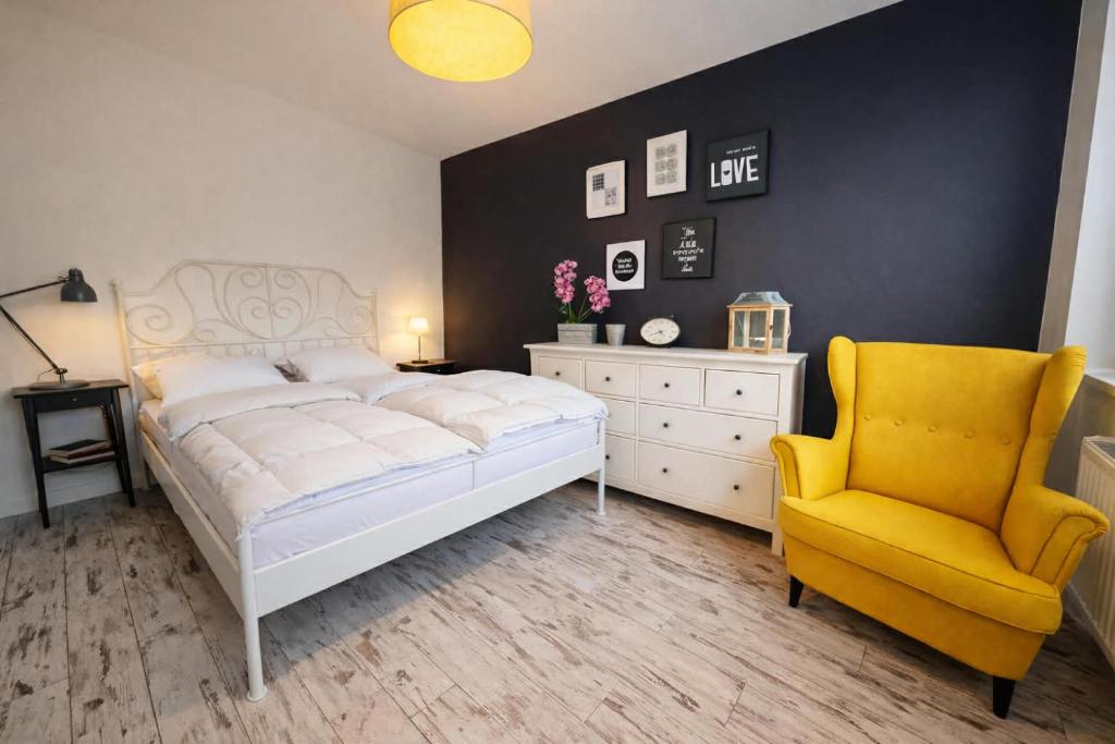 a bedroom with a white bed and a yellow chair at Zlatá Víla by Cañas Apartments V srdci mesta, len pár krokov od hlavného námestia in Rimavská Sobota