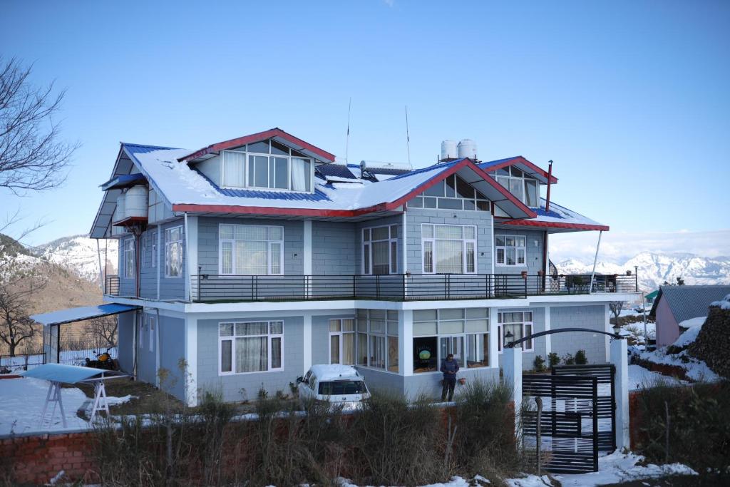 a large white house with snow on the roof at Village Crown in Mundaghat 