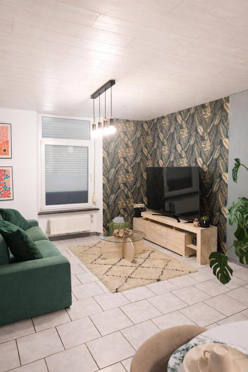 a living room with a green couch and a television at La maison des Oiseaux in Martelange