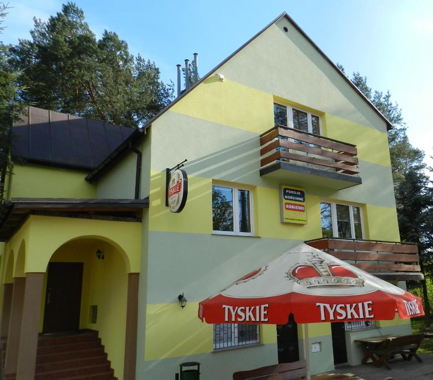 un edificio amarillo con sombrilla y anofeo en Pokoje Gościnne Przystań KAJA w Sobieskach nad Wkrą, en Sobieski