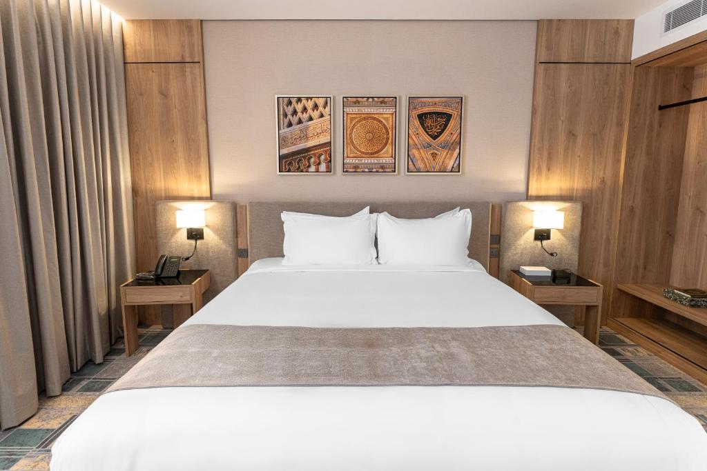 a bedroom with a large white bed with two lamps at فندق آفال AVAL Hotel in Medina