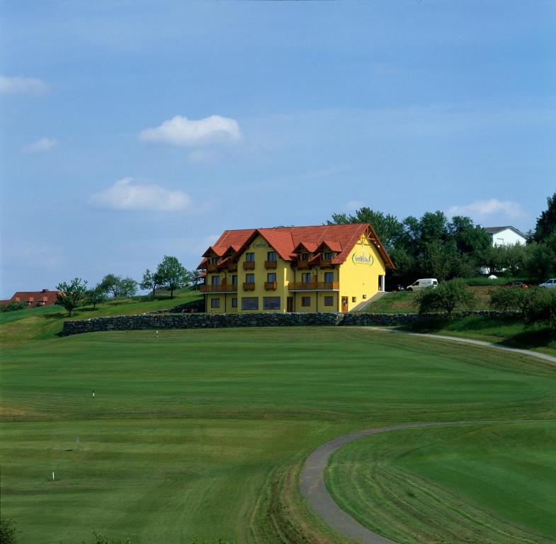 ein gelbes Haus auf einem grünen Feld in der Unterkunft Kunstcafe Rooms in Stegersbach