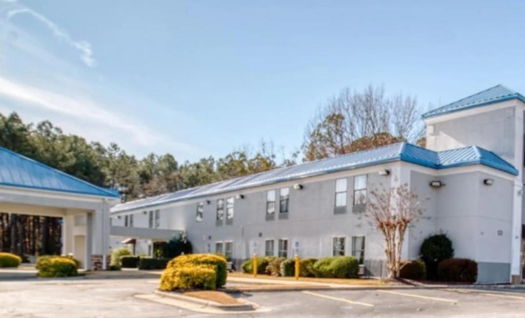 a large white building with a parking lot at Zanesville Inn in Zanesville