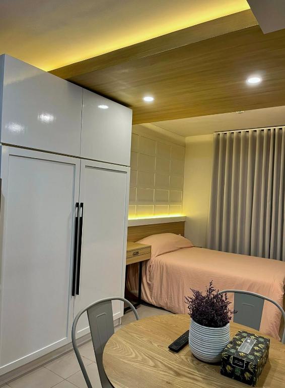 a bedroom with a bed and a table and a cupboard at Suite Talie Cebu Cozy Modern Stay with Pool & Netflix in Lapu Lapu City