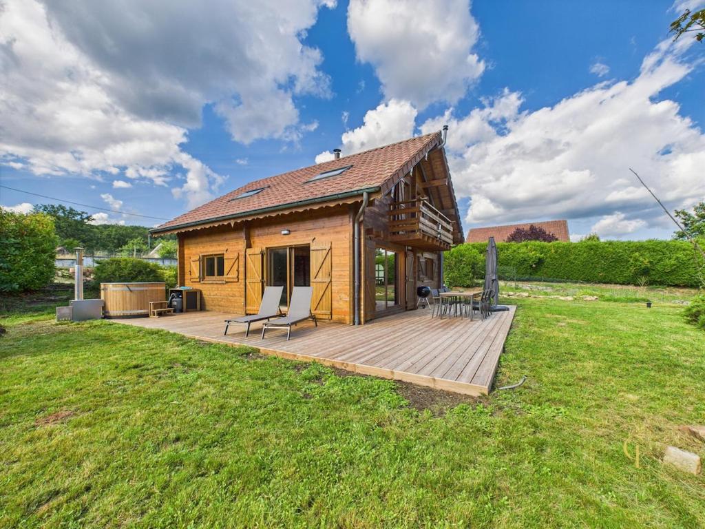 a log cabin with a deck in a field at Cozy chalet with Nordic bath in Plancher-Bas
