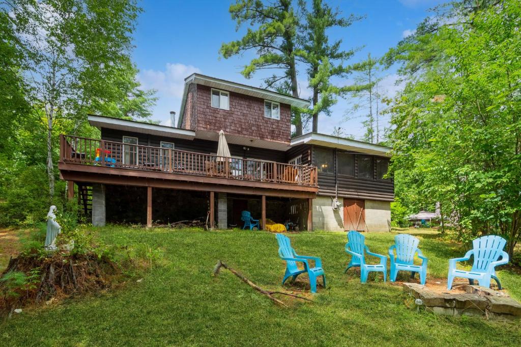 a house with a deck and chairs in the yard at Adirondacks in Style! Lake House w/ Deck, Fire Pit in Hadley