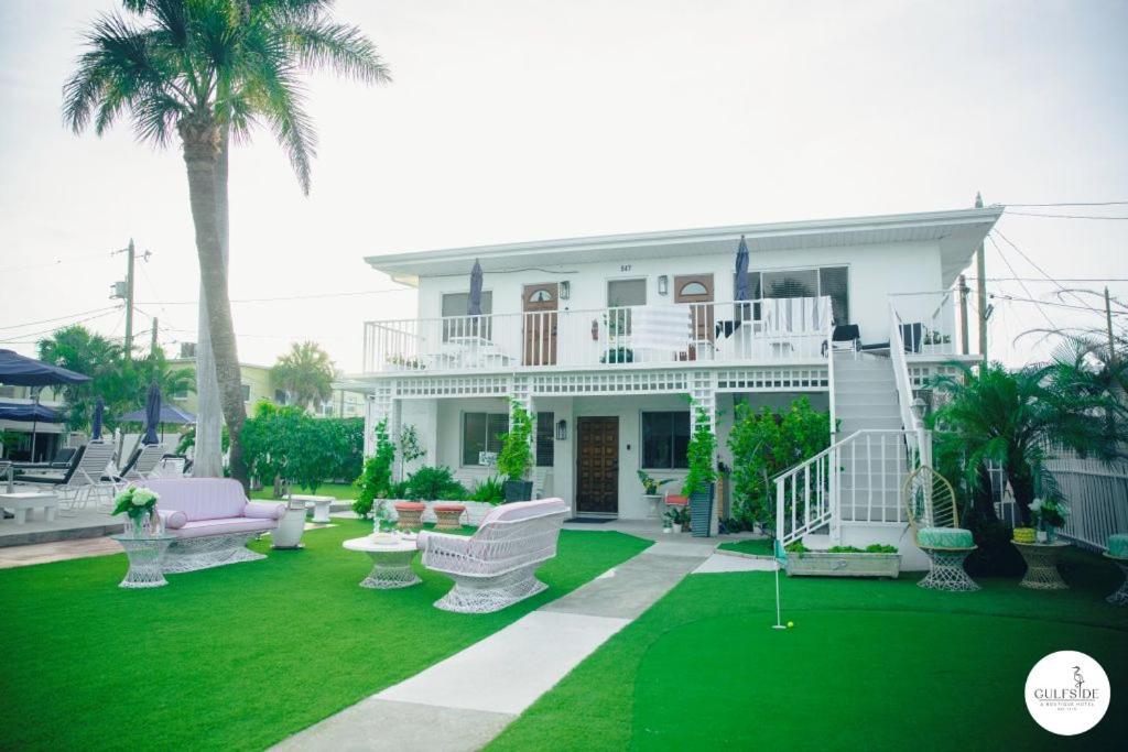a house with white furniture and a green lawn at Gulfside Resort Unit 9 in St. Pete Beach