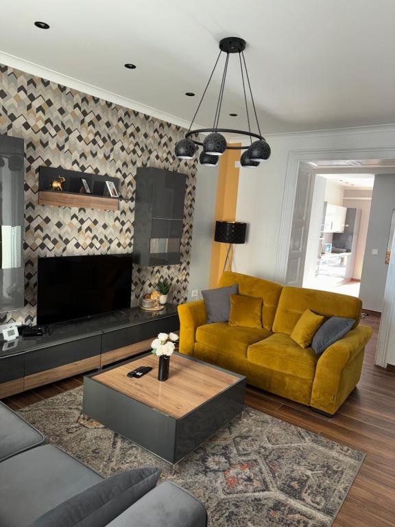 a living room with a yellow couch and a tv at Apartman Golden in Senta