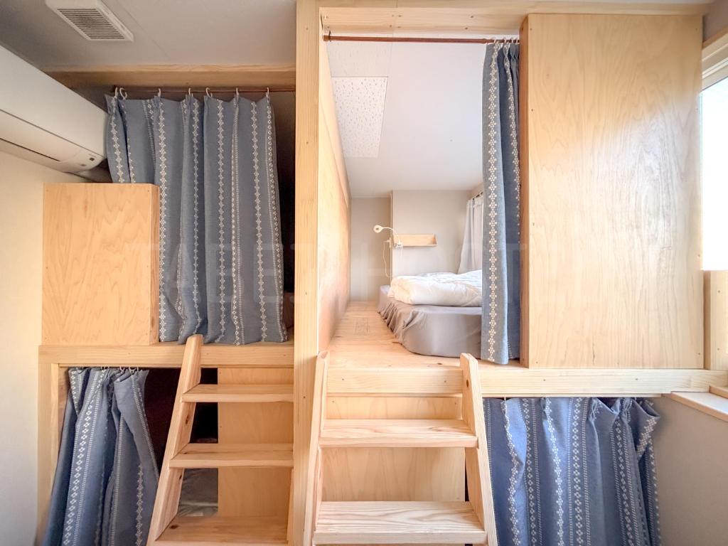 a tiny house with blue curtains and a bed at Fukuoka Tabiji Hostel 福岡旅路ゲストハウス in Fukuoka