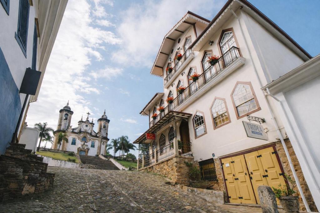 a building with yellow doors and a church in the background at Teatro Hotel Boutique in Ouro Preto