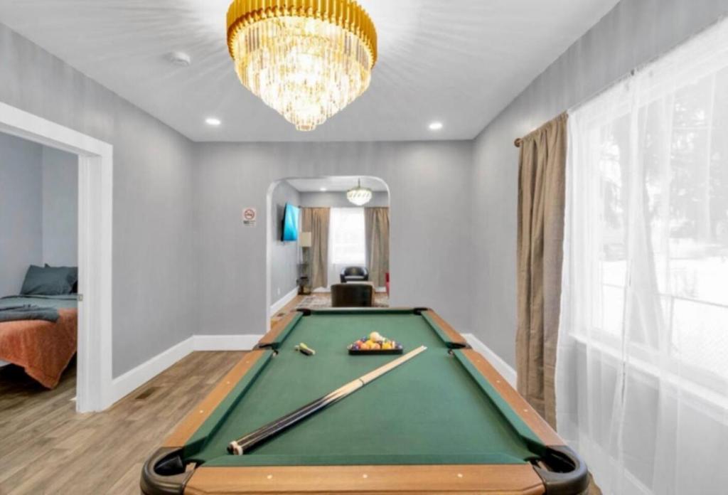a living room with a pool table and a chandelier at Cozy Corner Buffalo Getaway in Buffalo