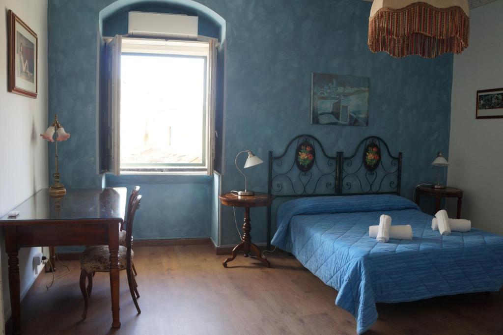 a bedroom with a bed and a desk and a window at Risveglio Ibleo in Ragusa