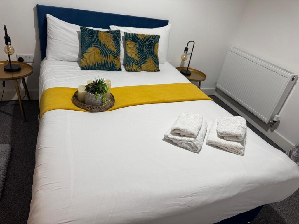 a large bed with towels and a plant on it at Heathrow central suites in Colnbrook