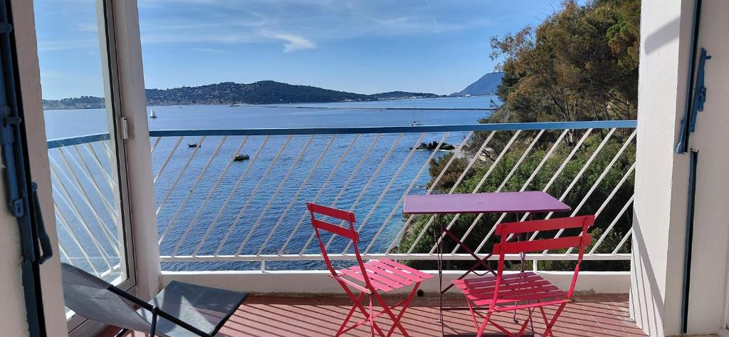 two chairs and a table on a balcony with a view of the water at Appartement Le Cap in Toulon