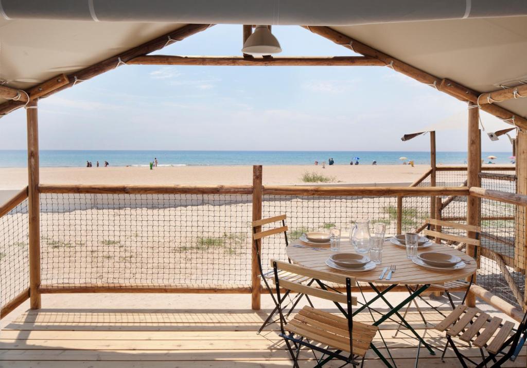 uma mesa e cadeiras num deque na praia em Camping Gavina Creixell em Creixell