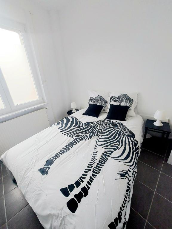 a bed with a black and white comforter at Lumière Luxembourg in Russange