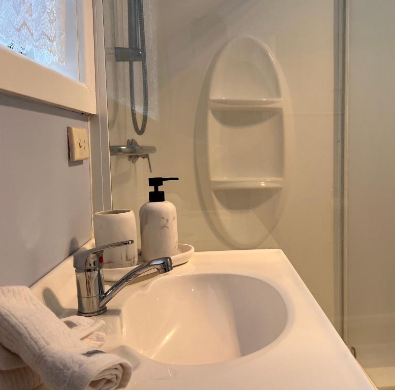 a white bathroom with a sink and a shower at Howrah Apartment in Howrah