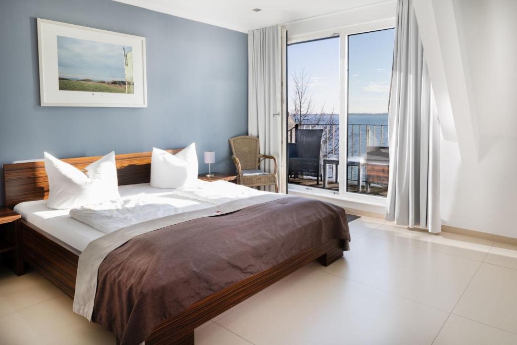 a bedroom with a large bed and a large window at Strandhotel Dranske in Dranske